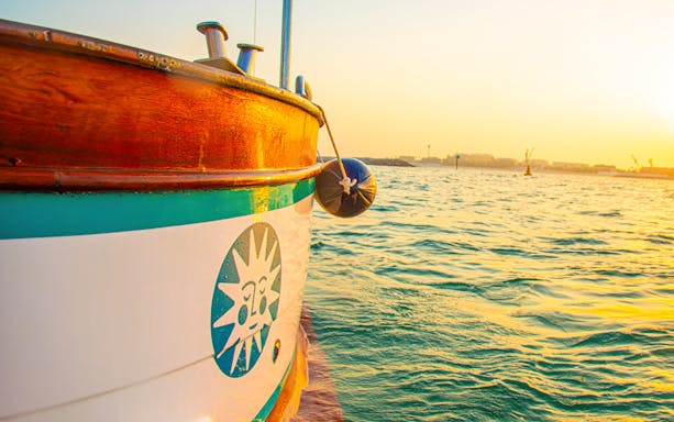 Traditional wooden boat on Dubai waters during sunset, part of Dubai Historical Tour.
