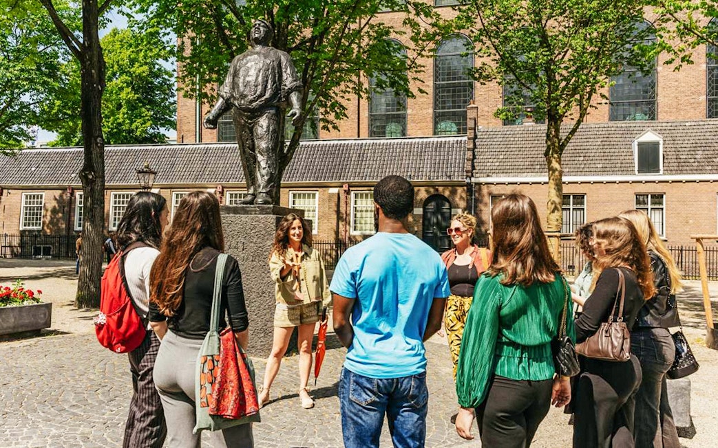 Guide with participants at the Statue of De Dokwerker in Amsterdam.