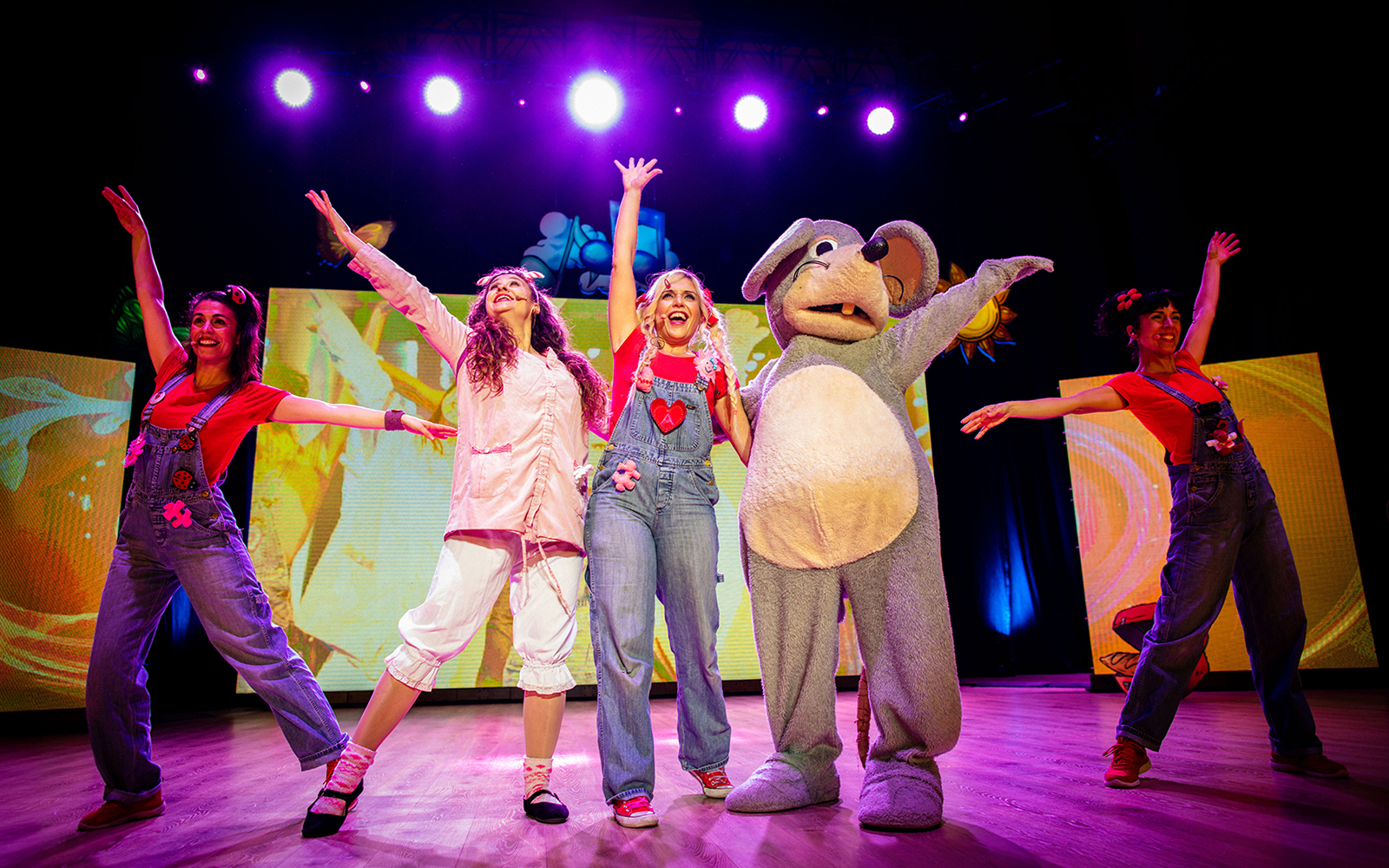Performers on stage celebrating Cantajuegos 20 Años with colorful lights and costumes.