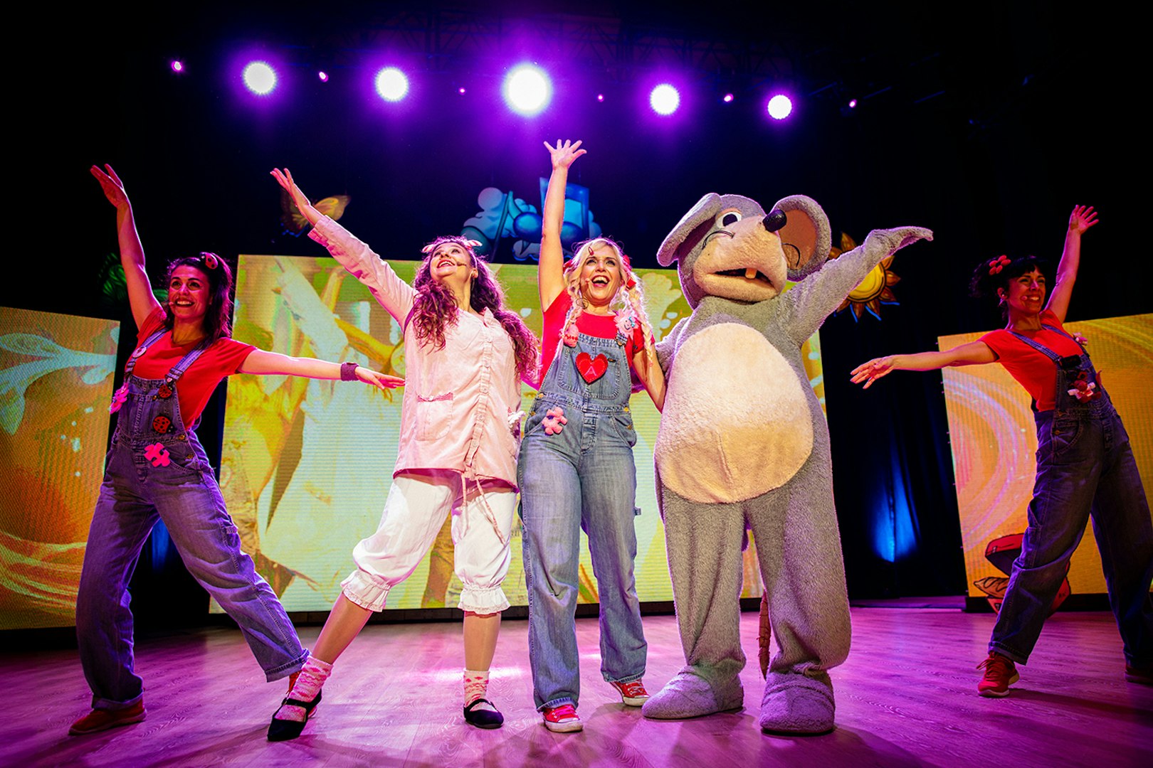 Performers on stage celebrating Cantajuegos 20 Años with colorful lights and costumes.