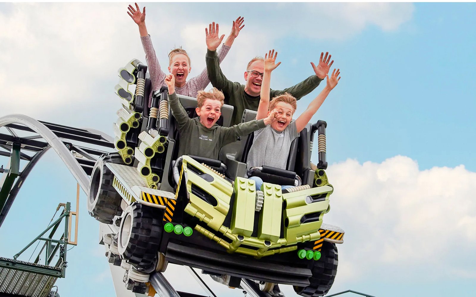 Guests riding a roller coaster at LEGOLAND Billund with hands raised in excitement.