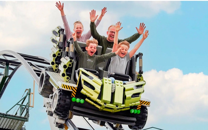 Guests riding a roller coaster at LEGOLAND Billund with hands raised in excitement.