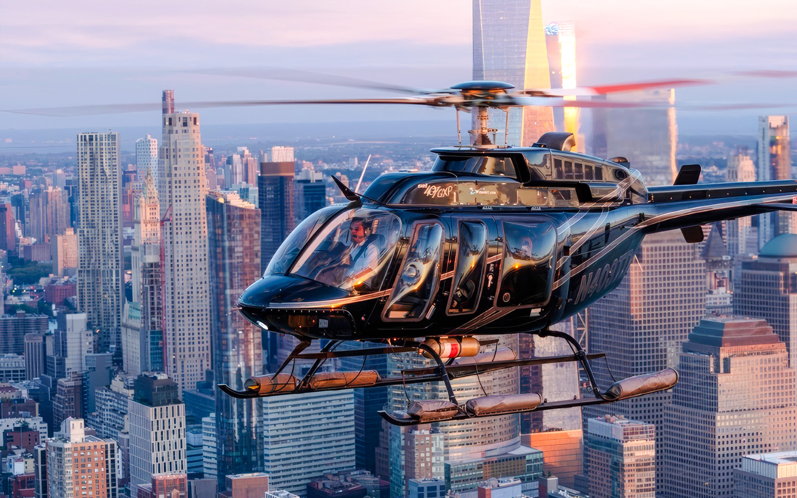 Helicopter flying over New York City skyline at sunset.