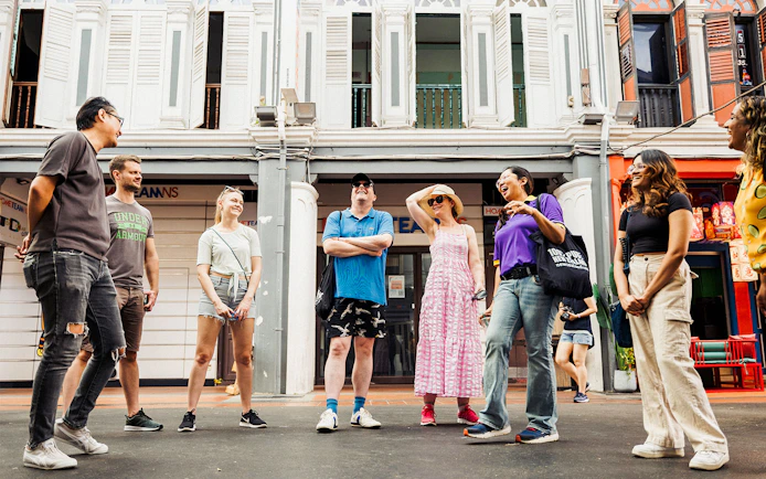 Group of tourists on a guided Michelin and local hawker food tour in a vibrant city street.