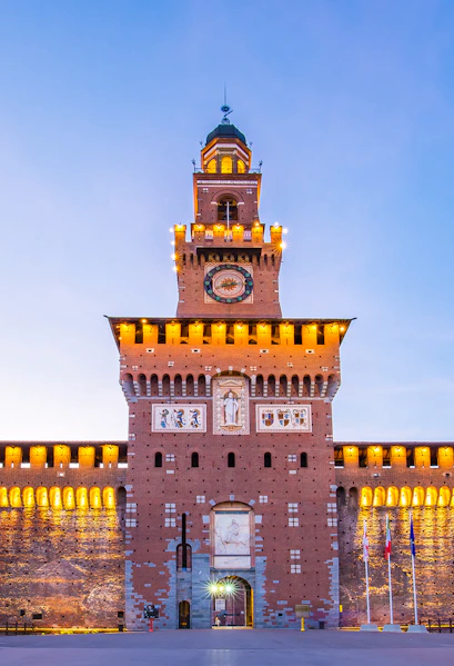 Sforza Castle facade in Milan, Italy, illuminated at dusk.