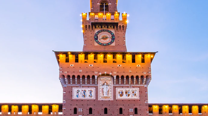 Sforza Castle facade in Milan, Italy, illuminated at dusk.