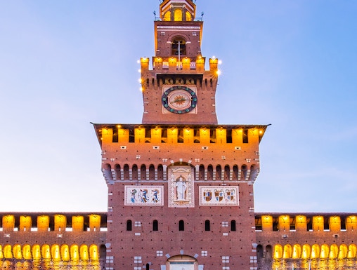 Sforza Castle facade in Milan, Italy, illuminated at dusk.