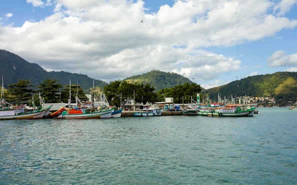 Boats docked at the pier in Angra dos Reis, Brazil, with lush hills in the background.