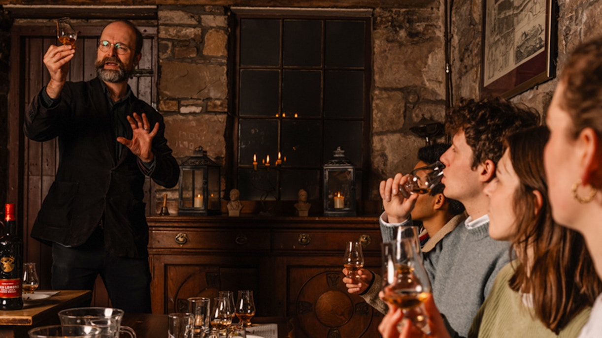 Whisky tasting session in an Edinburgh cellar with a guide explaining to a group.