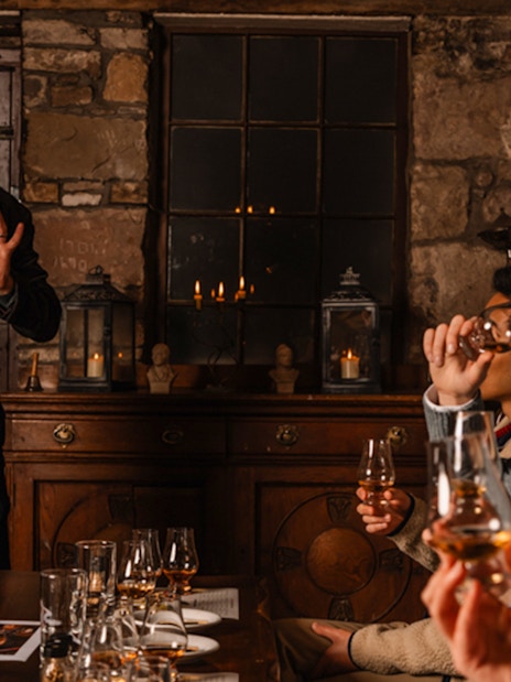 Whisky tasting session in an Edinburgh cellar with a guide explaining to a group.