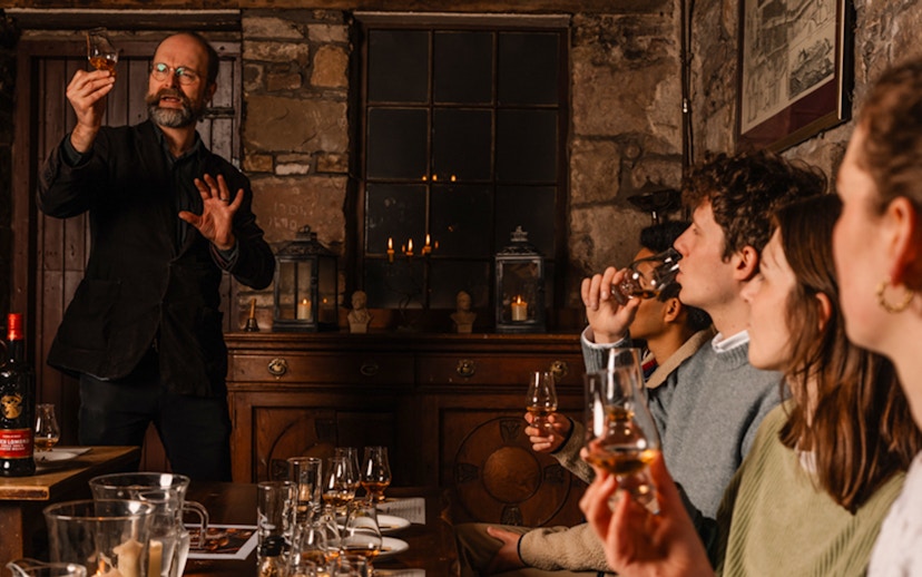 Whisky tasting session in an Edinburgh cellar with a guide explaining to a group.