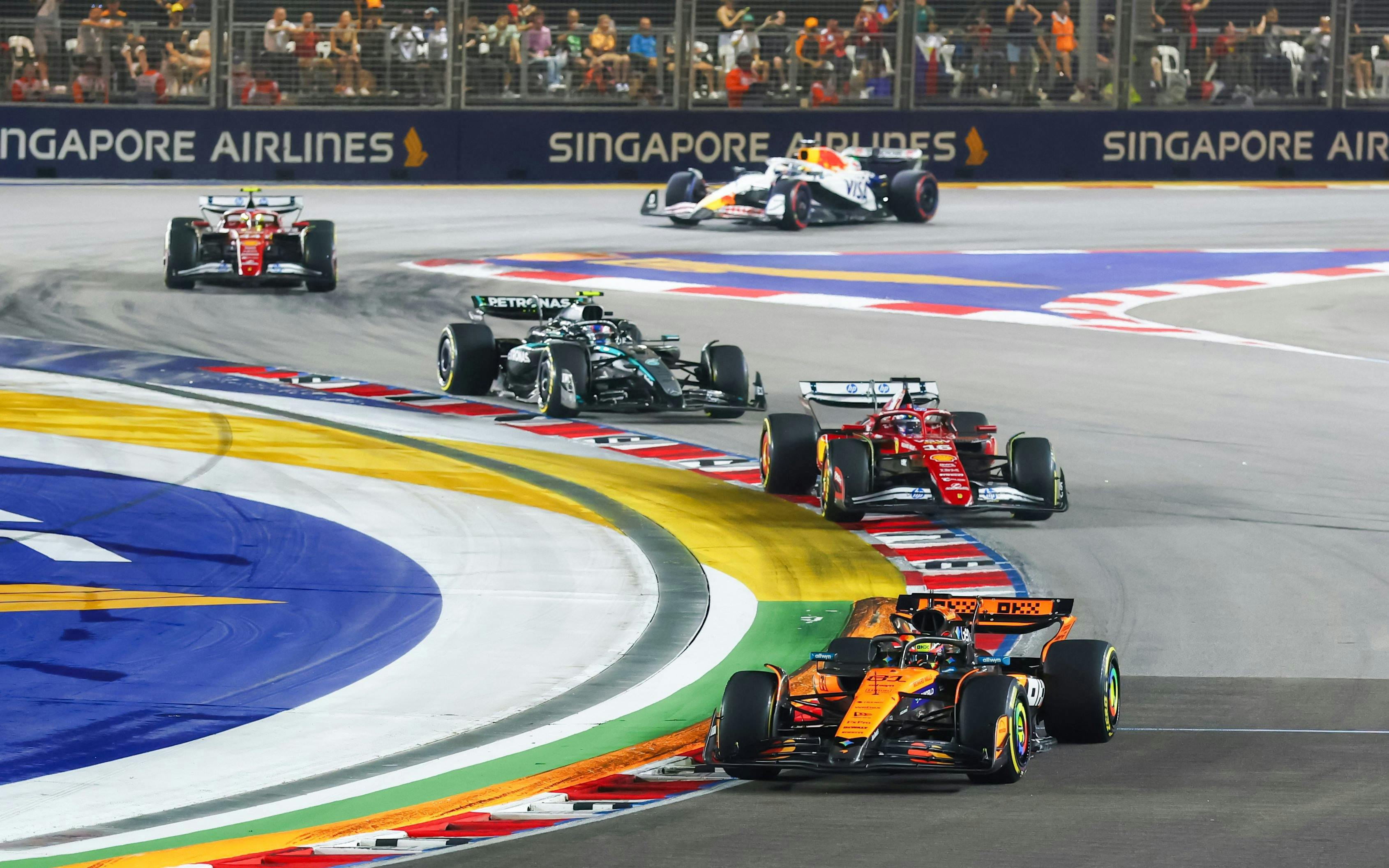 Formula 1 cars racing at Singapore Grand Prix night circuit.