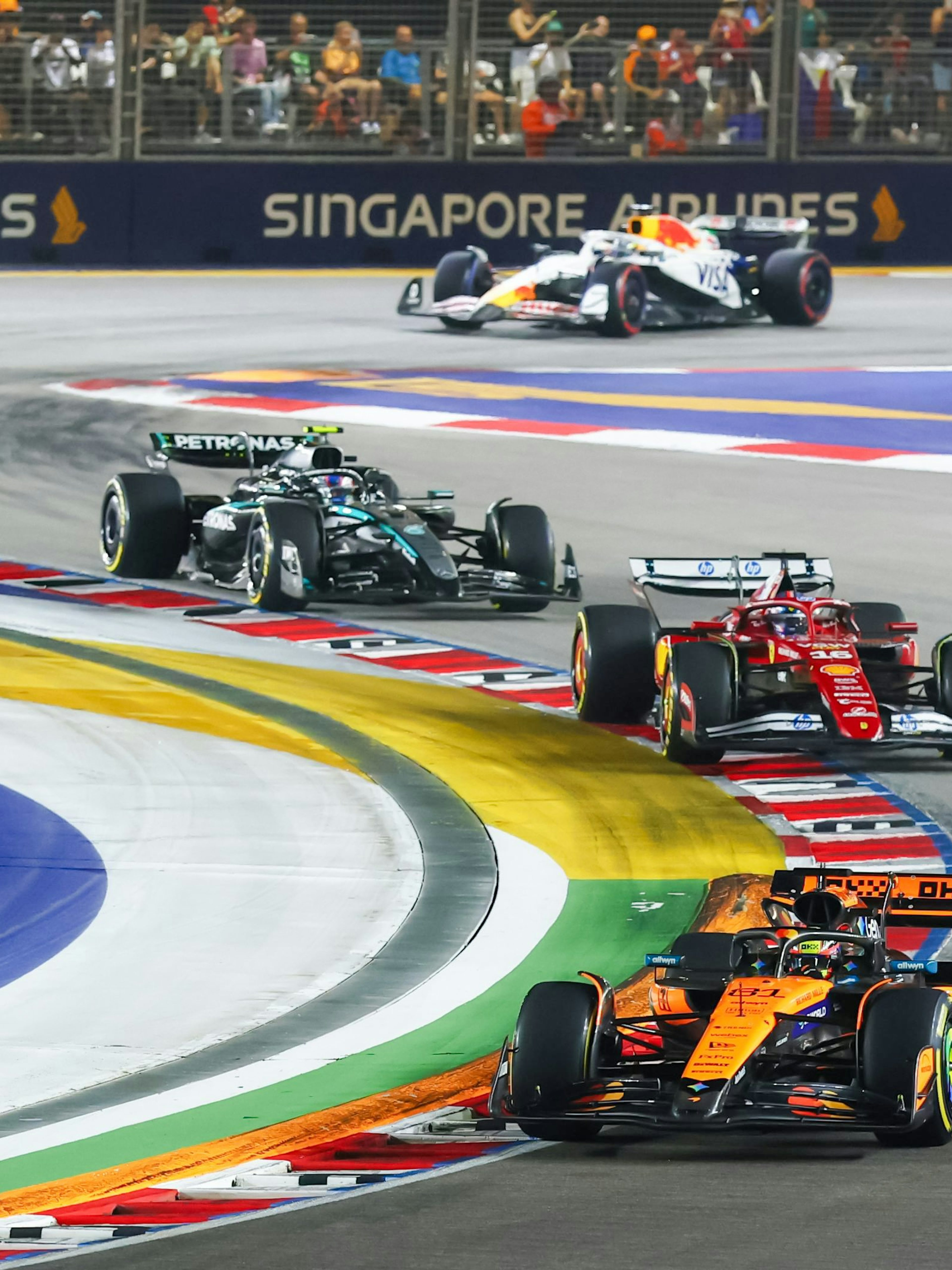 Formula 1 cars racing at Singapore Grand Prix night circuit.