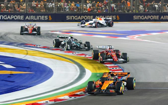 Formula 1 cars racing at Singapore Grand Prix night circuit.