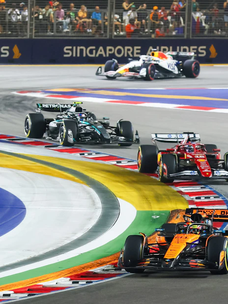 Formula 1 cars racing at Singapore Grand Prix night circuit.