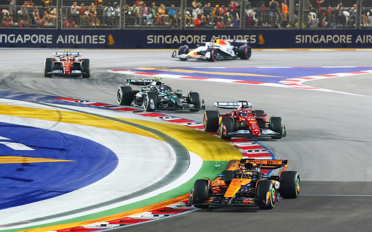 Formula 1 cars racing at Singapore Grand Prix night circuit.