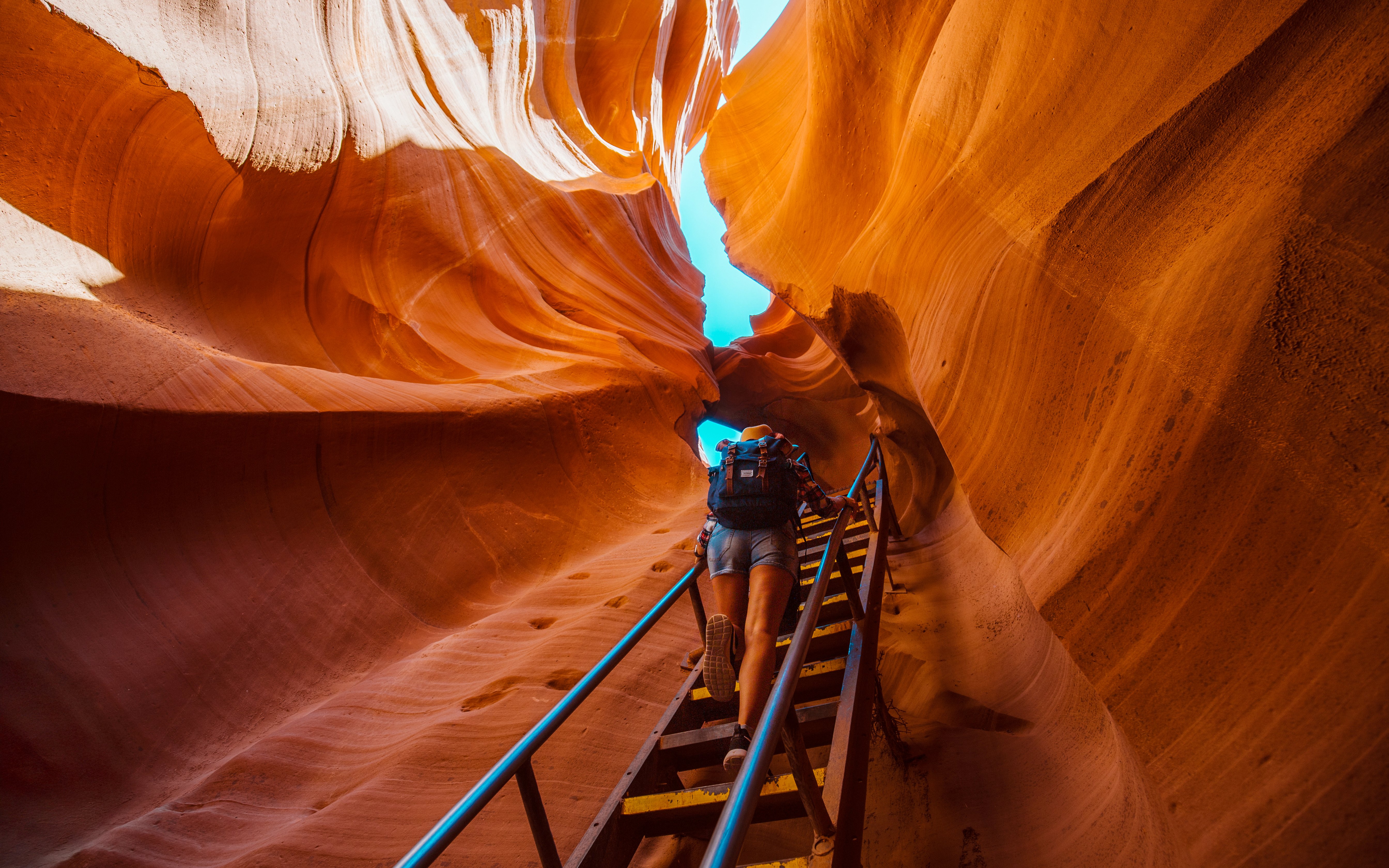 Backpacker climbing ladder in narrow Antelope Canyon passage.