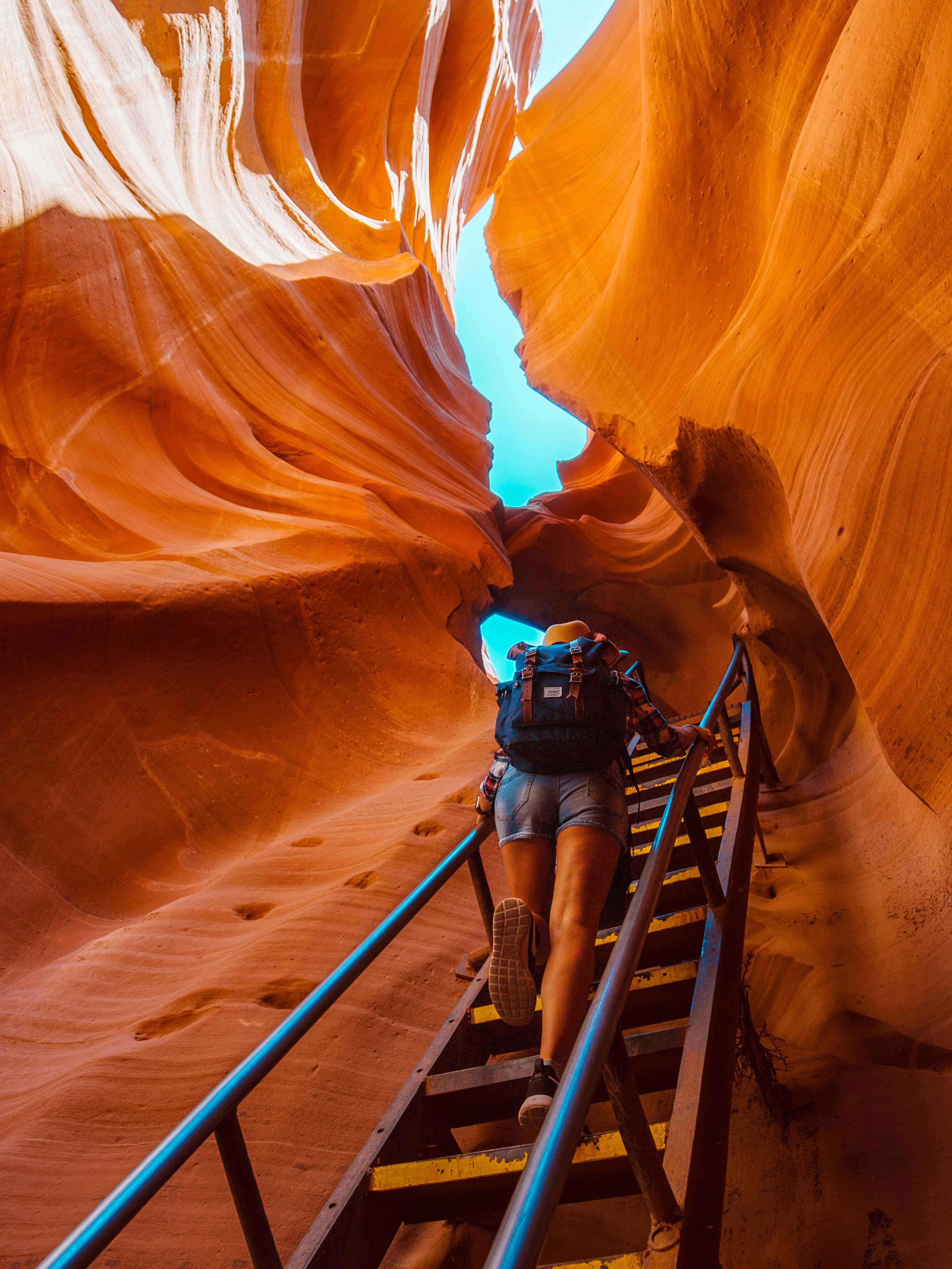 Backpacker climbing ladder in narrow Antelope Canyon passage.