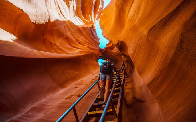 Backpacker climbing ladder in narrow Antelope Canyon passage.