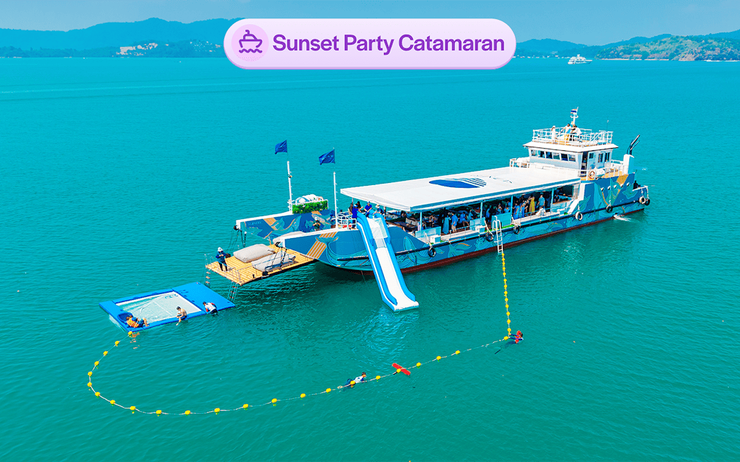 Luxury catamaran with slide and partygoers, sunset cruise near James Bond Island, Phuket.