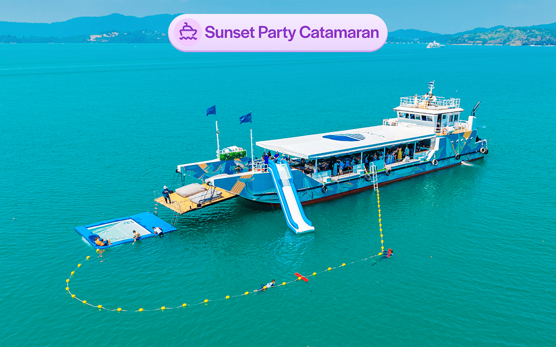 Luxury catamaran with slide and partygoers, sunset cruise near James Bond Island, Phuket.