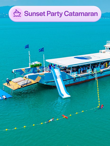 Luxury catamaran with slide and partygoers, sunset cruise near James Bond Island, Phuket.