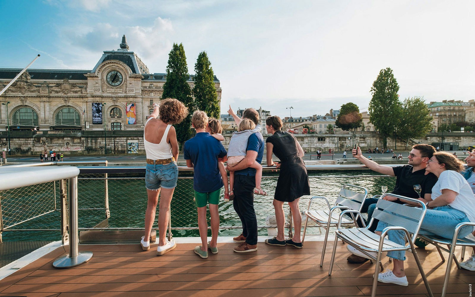 Family enjoying Vedettes de Paris guided cruise on the Seine River, Paris landmarks in view.