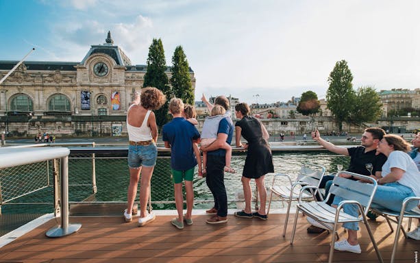 Family enjoying Vedettes de Paris cruise with view of Musée d'Orsay.