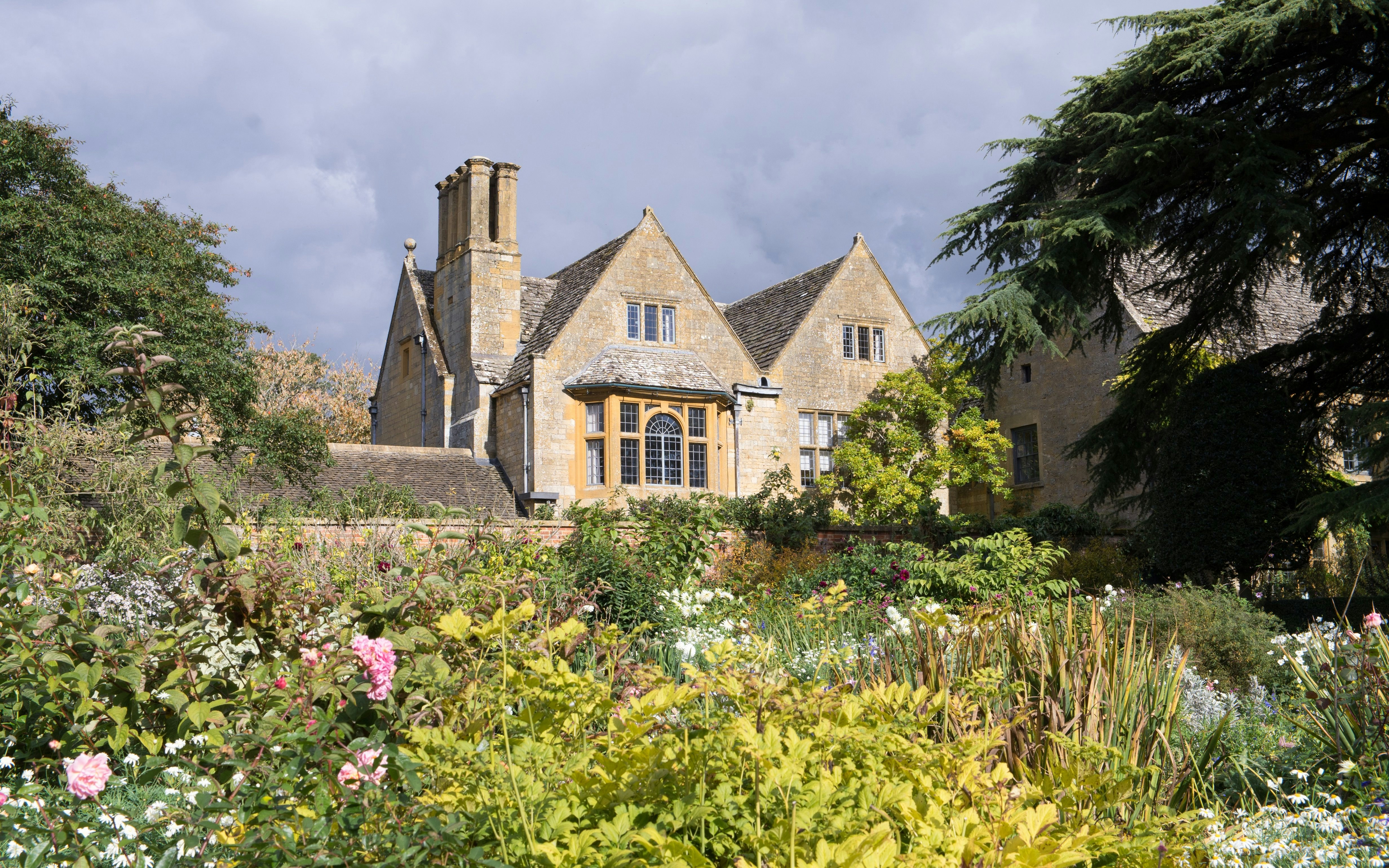 Hidcote Manor Garden in Cotswolds with historic stone building and lush floral landscape.