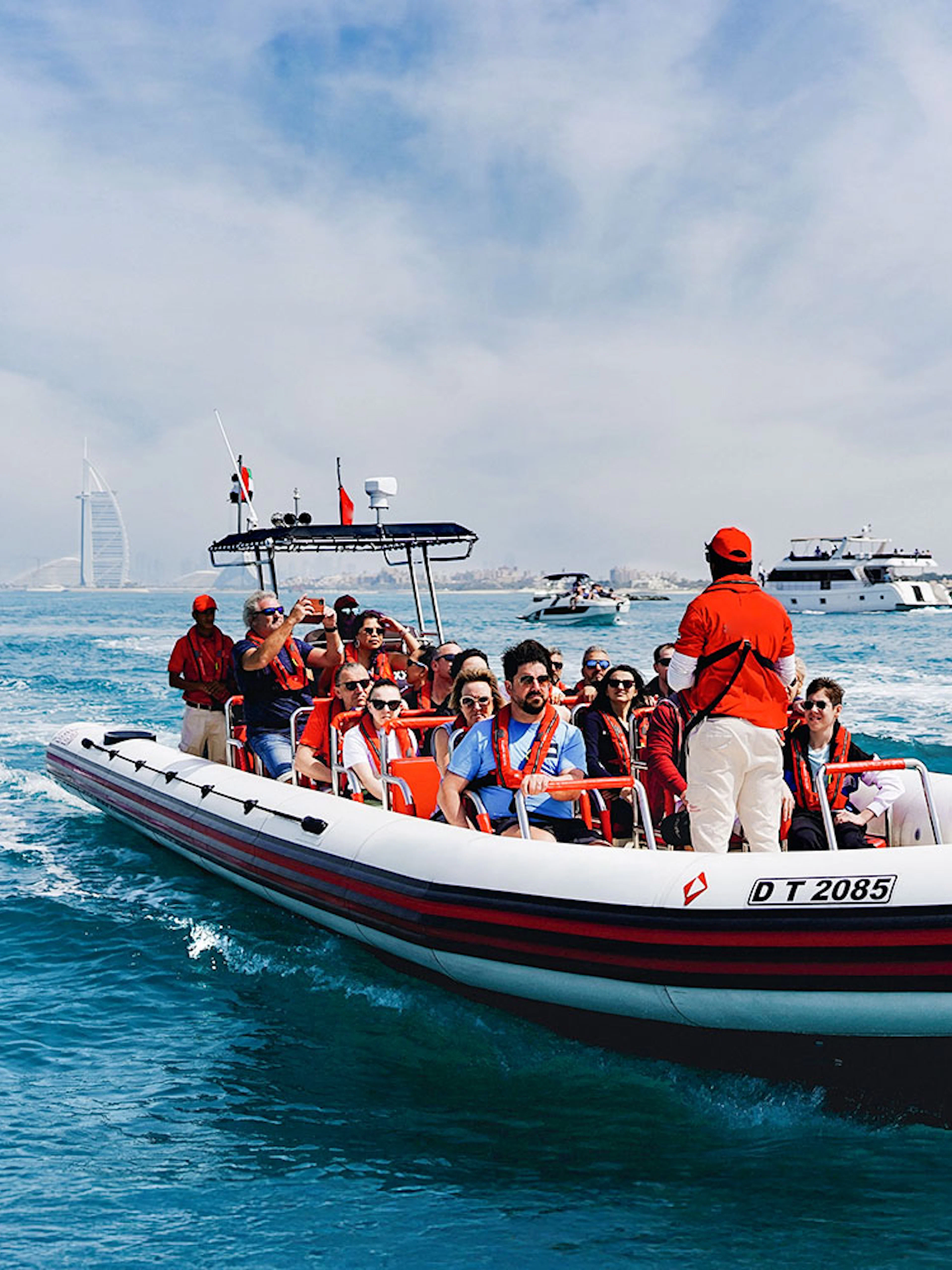 Speedboat tour with passengers near Dubai Marina, Burj Al Arab visible in the background.
