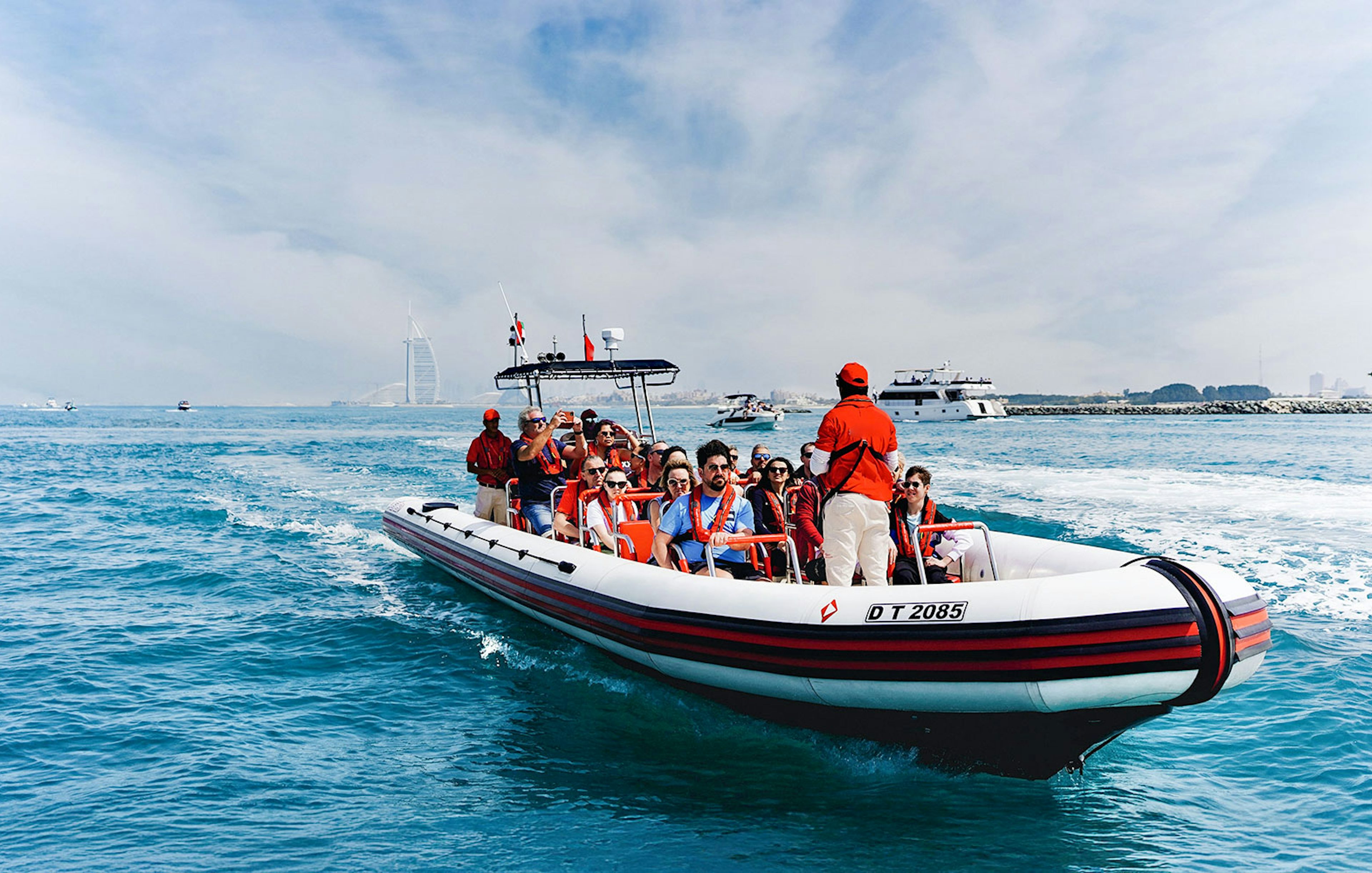 Speedboat tour with passengers near Dubai Marina, Burj Al Arab visible in the background.