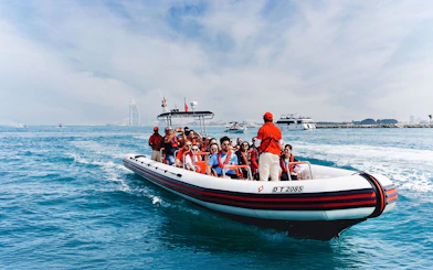 Speedboat tour with passengers near Dubai Marina, Burj Al Arab visible in the background.