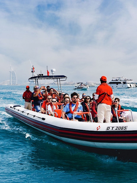 Speedboat tour with passengers near Dubai Marina, Burj Al Arab visible in the background.