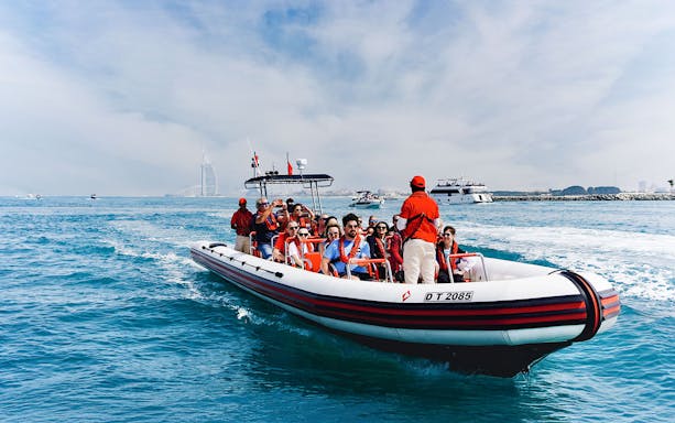 Speedboat tour with passengers near Dubai Marina, Burj Al Arab visible in the background.