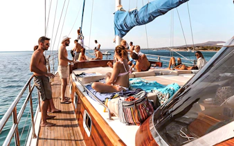 People relaxing on a yacht deck during a half-day Athens cruise with swim stop, lunch, and drinks.