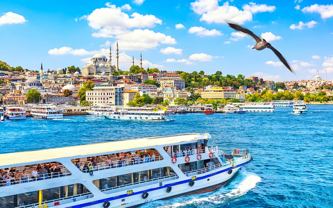 Hop-on-hop-off boat on the Bosphorus with Istanbul skyline and mosque in the background.