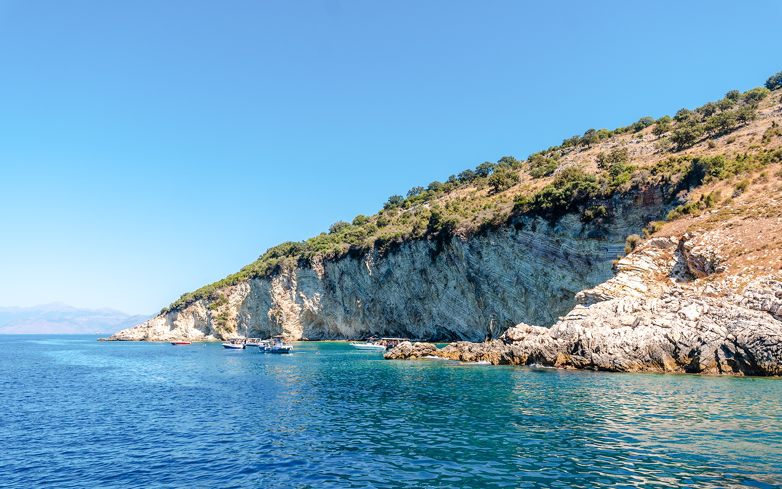 Boats near rocky cliffs at Gremina Beach, Albania.