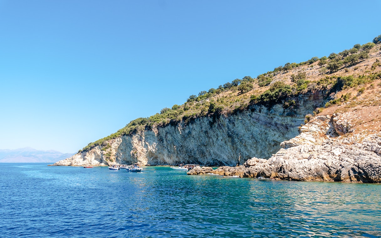 Boats near rocky cliffs at Gremina Beach, Albania.