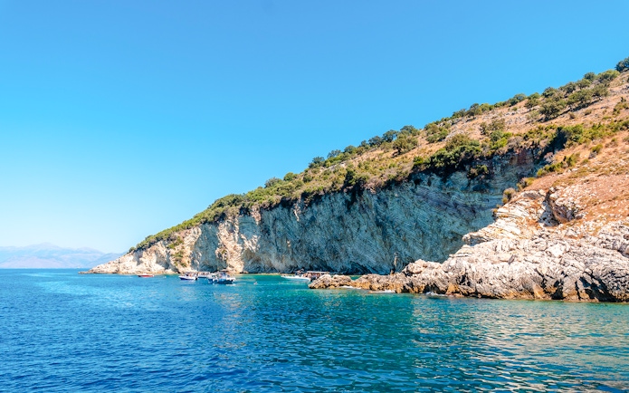 Boats near rocky cliffs at Gremina Beach, Albania.
