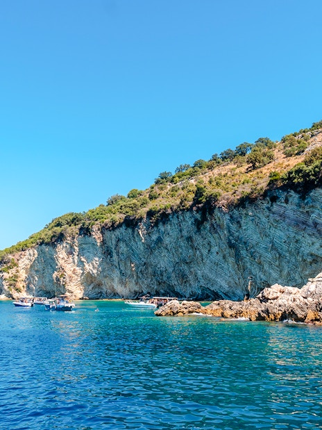 Boats near rocky cliffs at Gremina Beach, Albania.