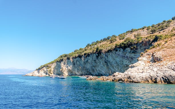 Boats near rocky cliffs at Gremina Beach, Albania.