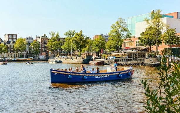 Canal boat with tourists on Amsterdam's Red Light District cruise.
