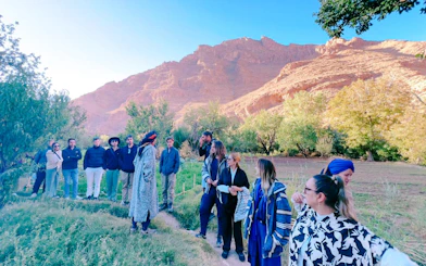 Group of tourists listening to a guide in front of Merzouga Dunes during a 3-day desert tour.