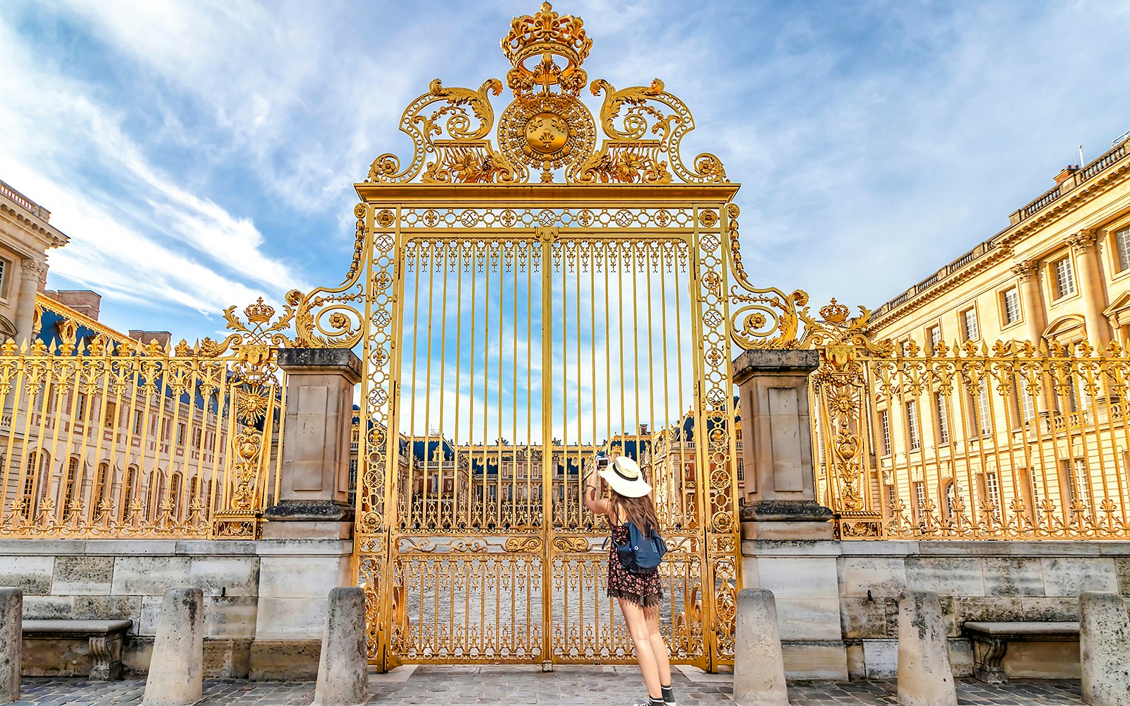 Golden gate at Versailles Palace facade, Paris, with visitor admiring.