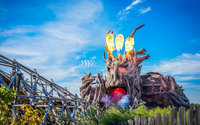 Heide Park wooden roller coaster with fiery tree sculpture.