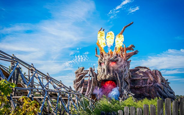 Heide Park wooden roller coaster with fiery tree sculpture.