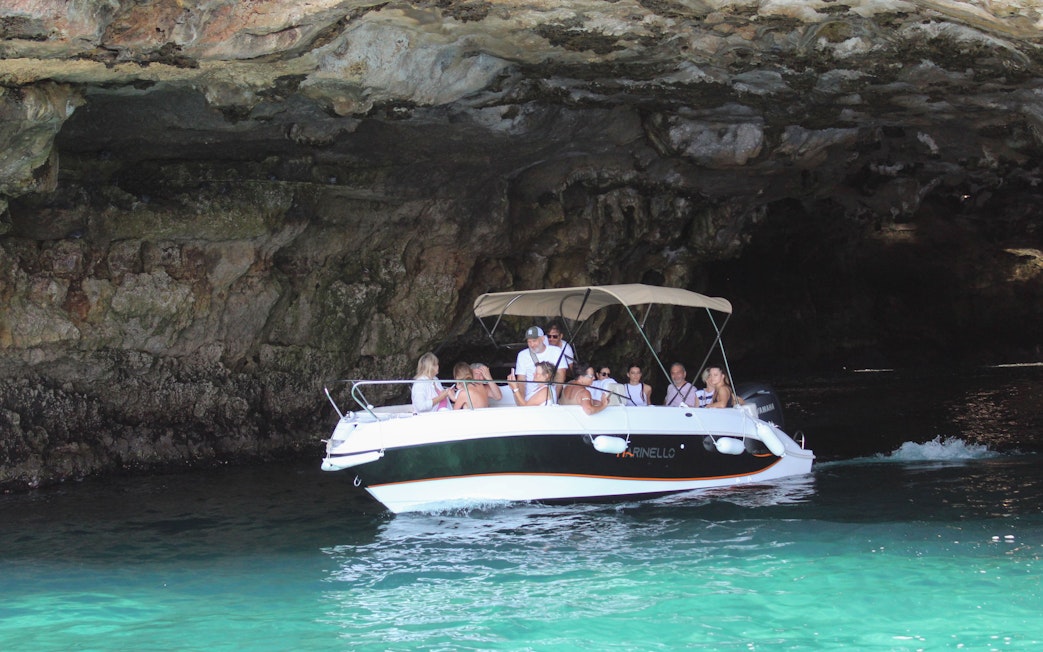 Boat navigating a cave on a tour in Polignano a Mare, Italy.