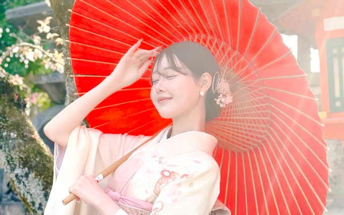 Person in traditional Japanese kimono with red wagasa umbrella.