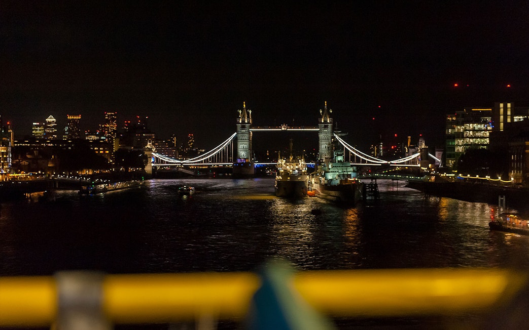Tower Bridge illuminated at night over the River Thames in London.