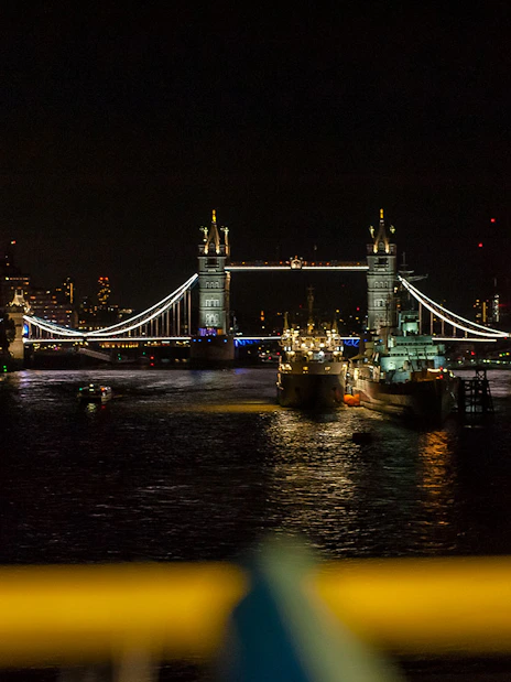 Tower Bridge illuminated at night over the River Thames in London.